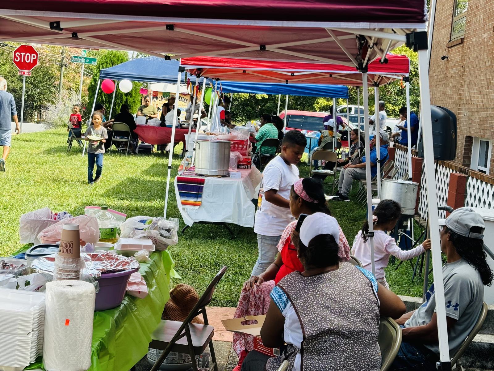 Familias compartiendo comida bajo carpas en un evento comunitario